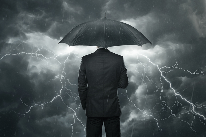 Mężczyzna z parasolem stojący w deszczu